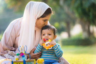 Arap anne ve küçük bebeği dışarıda oynuyorlar.
