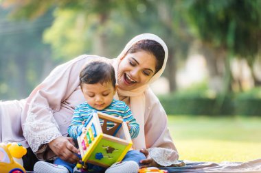 Arap anne ve küçük bebeği dışarıda oynuyorlar.