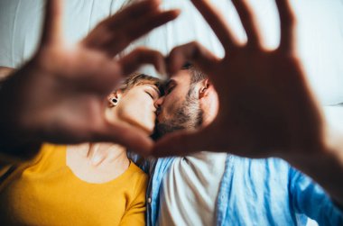 Genç çift yatakta dinleniyor ve eğleniyor. Selfie çekiliyor dur