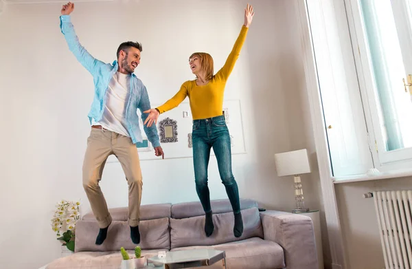 Pareja joven pasando tiempo juntos en casa. Hombre y mujer jumpi —  Fotos de Stock