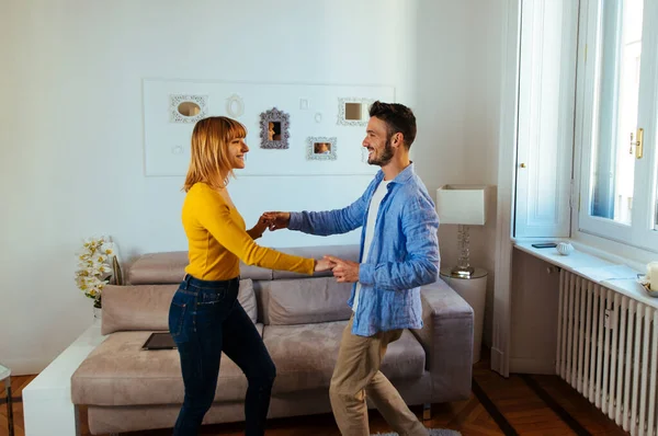 Νεαρό ζευγάρι περνάει χρόνο μαζί στο σπίτι. Άνδρας και γυναίκα χορεύουν — Φωτογραφία Αρχείου
