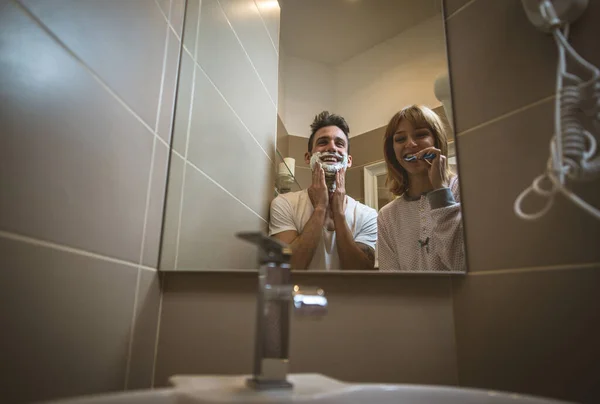 Kilka porannych zajęć. Mężczyzna i kobieta dzielą łazienkę. Golenie — Zdjęcie stockowe