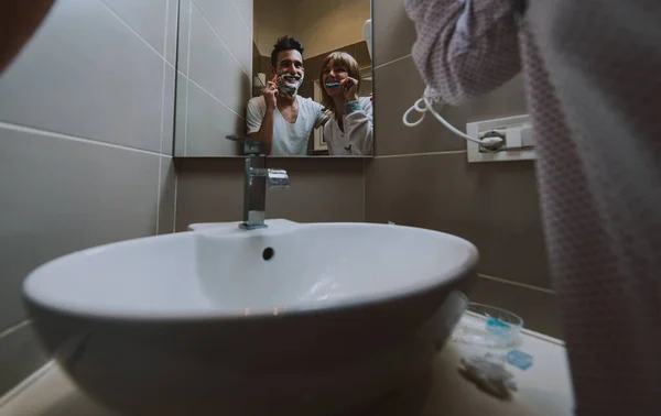 Pärchenmorgendliche Routine. Mann und Frau teilen sich ein Badezimmer. Rasieren — Stockfoto