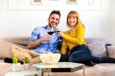Evde iki genç yetişkin, güzel bir çift rahatlıyor ve TV 'de film seyrediyor.