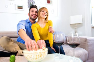 Evde iki genç yetişkin, güzel bir çift rahatlıyor ve TV 'de film seyrediyor.