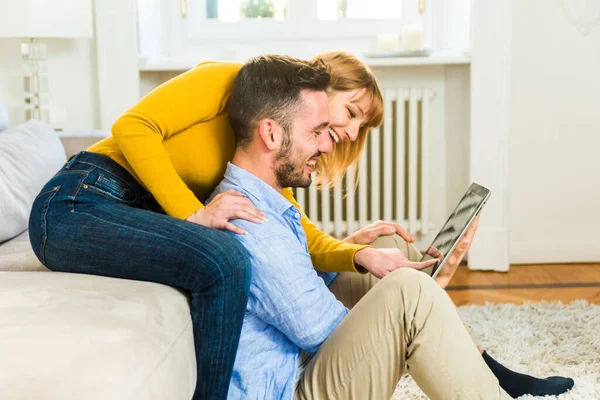 自宅で2人の若い大人 自宅でコンピュータタブレットを使用してオンラインで買い物をする美しいカップル — ストック写真