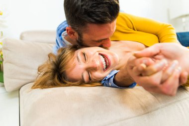 Evde iki yetişkin var. Mutlu çift kanepede sarılıyor.