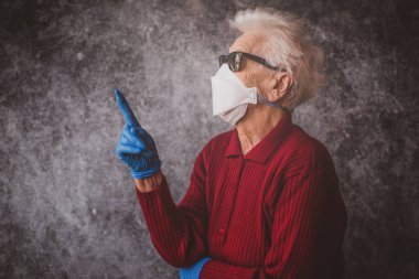 Old grandmother protect herself from coronavirus infection with medical gloves and respirator mask clipart