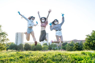 Koronavirüs döneminde bir grup Asyalı kız karantinadan sonra dışarı çıkıyor. Dışarıda maskeli genç kadınlar.