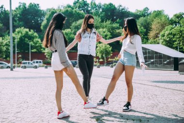 Koronavirüs döneminde bir grup Asyalı kız karantinadan sonra dışarı çıkıyor. Dışarıda maskeli genç kadınlar.