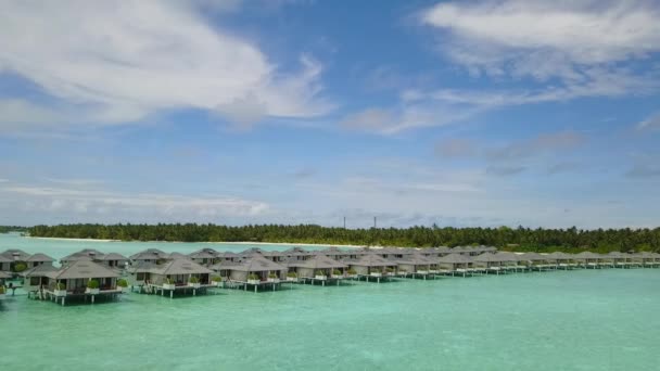 Niski kąt widzenia niebieskiej laguny z bungalowem z drona 4K — Wideo stockowe