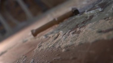 Bir adam masanın üzerinde yatan bir çekiç alır. Etrafı talaş dolu 4K görüntülerle çevrilidir.