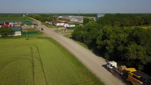 Drohnenschuss hinter LKW mit Mähdreschern in landwirtschaftlichem Betrieb — Stockvideo