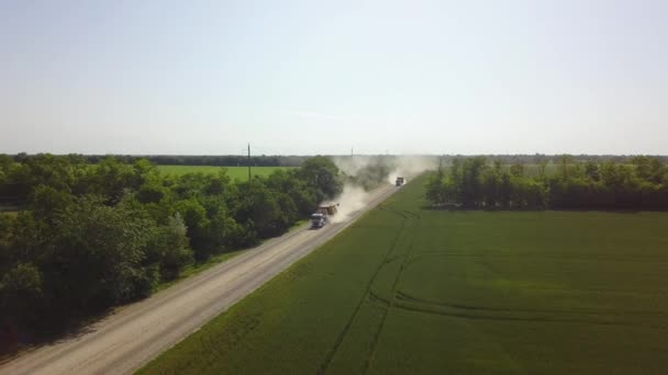 2 nákladní auta se pohybují na špatné silnici se spoustou prachu a dodávka kombinuje v zemědělství hospodářství Dron výstřel v 4K — Stock video