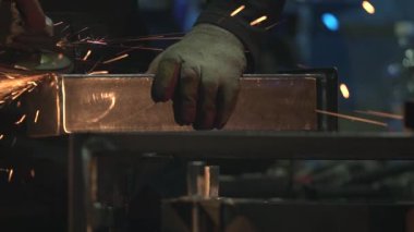 Beyaz adam atölyede metal öğütücüsünü metal fırçayla temizliyor. Kıvılcımlar. Sonunda inanılmaz bir bokeh.