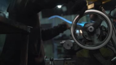 Kafa bandı ve koruyucu tulum giyen profesyonel bir vatman küçük tanker atölyesinde dikkatlice metal torna yapıyor..