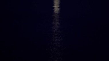 Kamera ay yolu boyunca yavaş yavaş Ay 'dan gece yarısı sakin mavi denize iniyor..