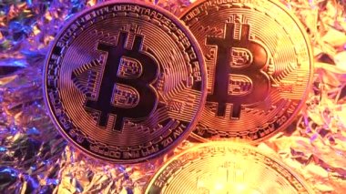 Masada üç Bitcoin BTC var. Süper Macro şutu. Kamera madeni paradan uzaklaşıyor ve diğerlerini gösteriyor. Altın ve mavi neon ışıklı sikkeler. Yarı yarıya. Şifreli para birimi