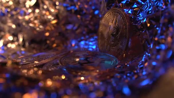 Schöne Nahaufnahme von Bitcoin BTC aus niedrigem Winkel. Kryptomünzen rotieren auf dem Tisch mit schönem Gold, blauem Licht und erstaunlichem Hintergrund. Weitere Kryptomünzen im Vordergrund. — Stockvideo