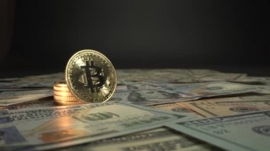 Kamera bugün altın Bitcoin BTC ile ana şifreleme madeni parasıyla ilerliyor. Masada binlerce Amerikan doları ve paranın arkasında siyah bir zemin..