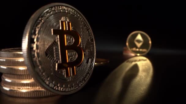 Monnaie crypto argent et bronze BITCOIN BTC et Etherium avec reflet doré. Fond noir. Focus passe d'une pièce à l'autre . — Video