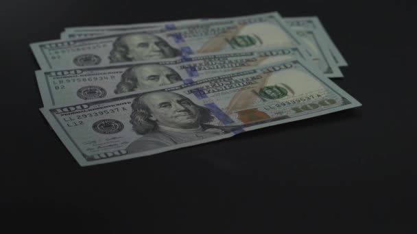 Мужская рука положила американские доллары на черный стол после торговли. Банкноты номиналом 100 долларов. 4K видео — стоковое видео