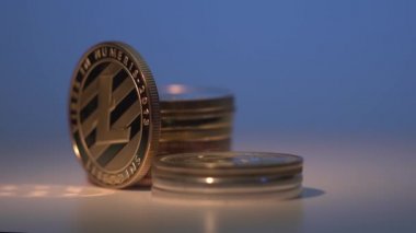 Litekoin, başka bir altın kripto sikke ve yüzeyde yansıma ile çevrili siyah yüzeyde dönüyor. Harika bir gradyan mavi arka plan. Madencilik parası.