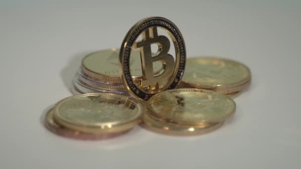 Moneda de oro Bit coin BTC gira en el sentido de las agujas del reloj rodeado de otras monedas criptográficas exitosas en la superficie blanca. Moneda del futuro . — Vídeos de Stock