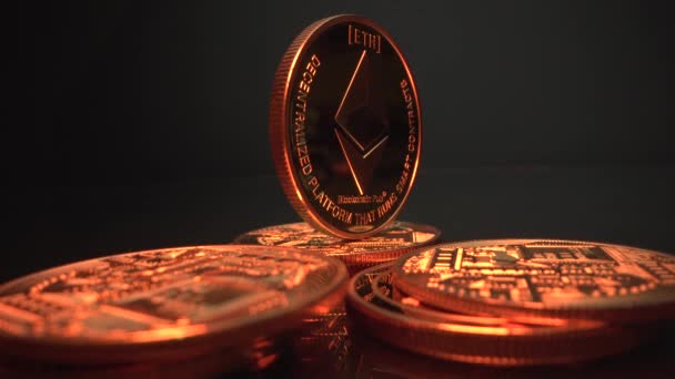 La luz de bronce ilumina varias monedas criptográficas ETH ETERIUM en la superficie negra. Dinero criptográfico. Moneda del futuro. Vídeo 4K — Vídeo de stock