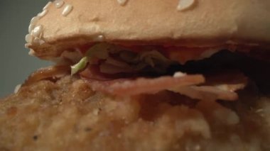 Domatesli, etli, sosisli, otlu ve susamlı taze pişmiş cheeseburger. Beyaz arka plan. Hamburger tabakta saat yönünde döner