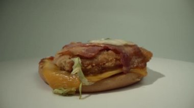 Bir aşçı lezzetli bir susamlı burgerin üstüne uzanır. Hamburger beyaz arkaplanda bir tabakta döner