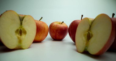 Beyaz bir masada tam ve dilimlenmiş kırmızı taze elmalar. Makro yiyecek.