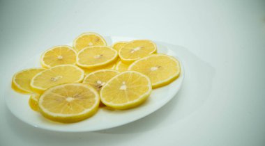 Beyaz arka planı olan beyaz camlı bir yerde bir sürü taze limon var.