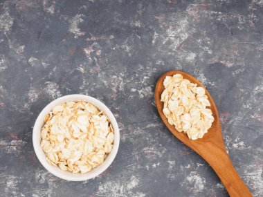 Beyaz fincanlarda yulaf ezmesi ve koyu beton bir sırt üzerinde tahta kaşıklar.