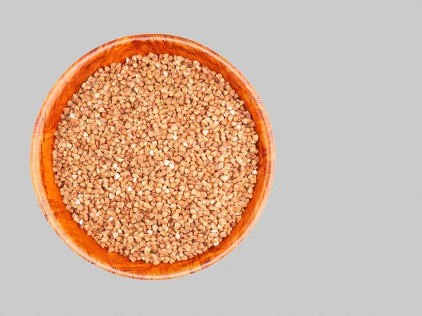 Buckwheat groats in a bamboo bowl on a gray background. Weight l — Stock Photo, Image