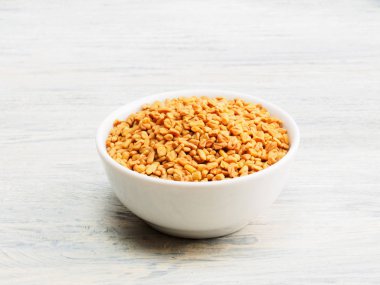 Beyaz ahşap arka planda, çanakta bir FenuGreek. Hint mutfağı, 