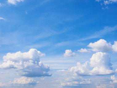 Beyaz bulutlar mavi gökyüzüne karşı. Güneş ışınları tarafından aydınlatılıyor.