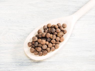 Beyaz arka planda tahta kaşıkta Allspice. Hint mutfağı, 