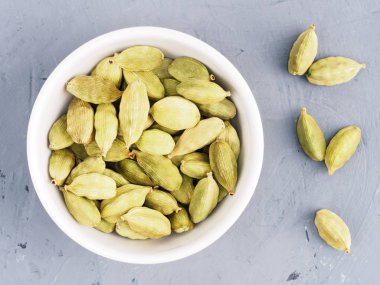 Beyaz kasede yeşil kakule ve gri üzerinde yeşil kakule tohumu. 