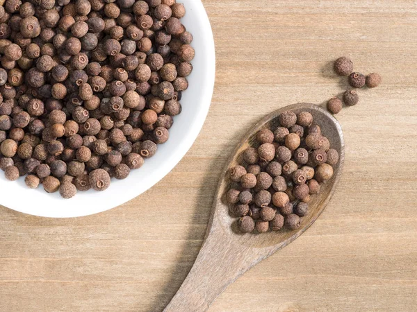 Allspice em tigela branca e colher em um fundo de madeira marrom. I — Fotografia de Stock