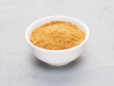 Spice masala in white ceramic cup on gray concrete background. H