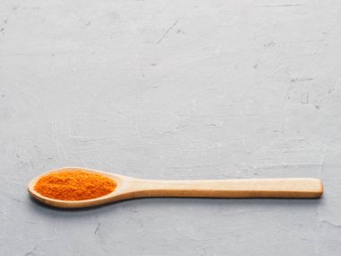 Spice red chili pepper in wooden spoon on gray concrete backgrou