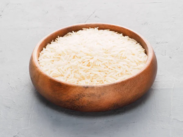 Basmati rice in wooden cup on gray concrete and beige fabric bac — Stok fotoğraf