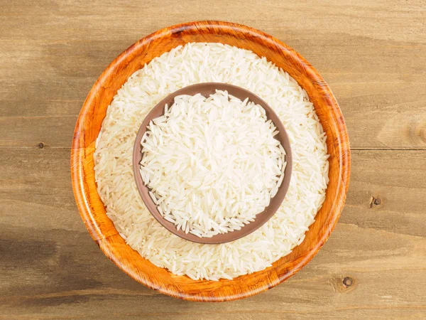 Рис в миске и глиняная тарелка на коричневом деревянном фоне. Индийский c — стоковое фото