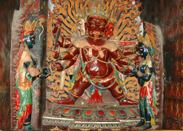 Brown Tibetan deity statue in a golden crown with six arms in a — 스톡 사진