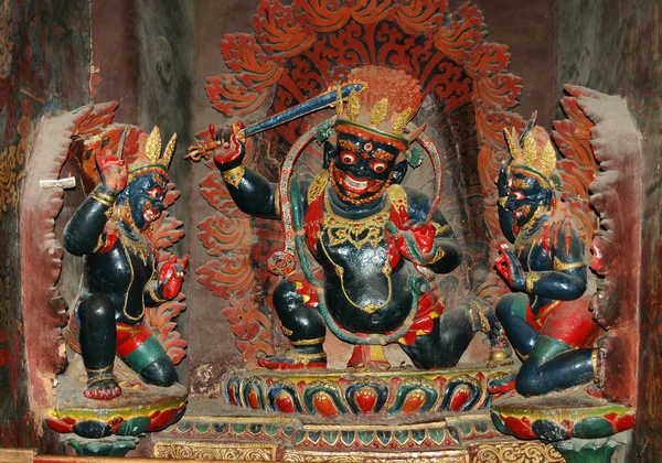 Tres estatuas de deidades tibetanas negras con coronas de oro en un mon — Foto de Stock