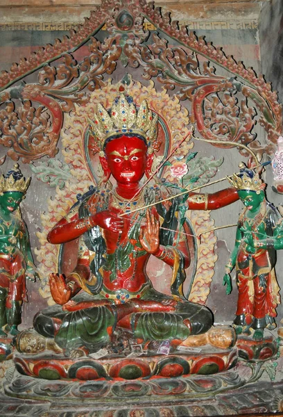 An ancient sacred statue of a red deity with a stretched bowstri — 스톡 사진