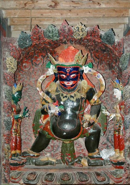 Ancient sacred statue of a deity with a green body in a blue mas — 스톡 사진