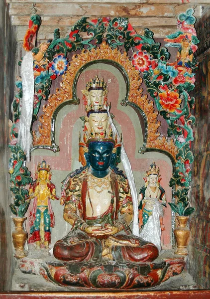 Una antigua estatua de deidad tibetana blanca con tres cabezas en un mona —  Fotos de Stock