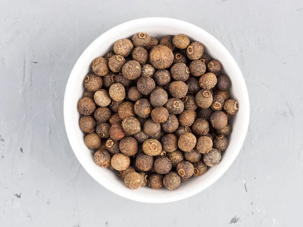 Allspice em uma tigela branca em um fundo de concreto cinza. Saudável — Fotografia de Stock